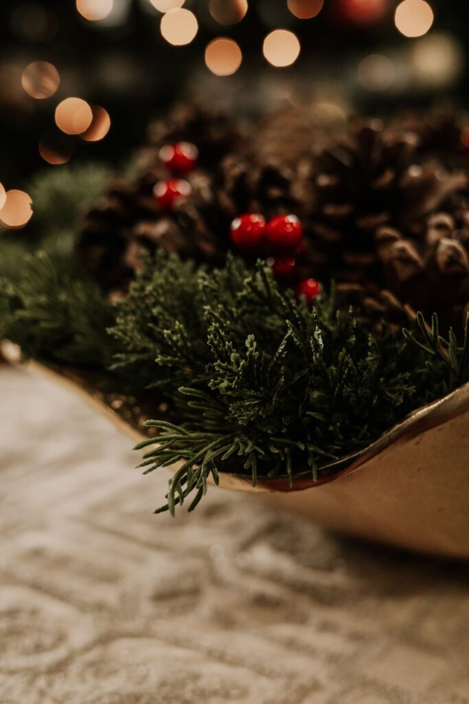 Decorative bowl filled with pinecones, evergreen sprigs and red berries