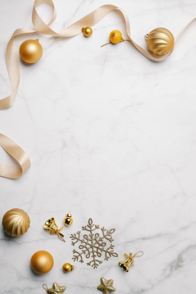 Gold ornaments and cream ribbon arranged on white marble