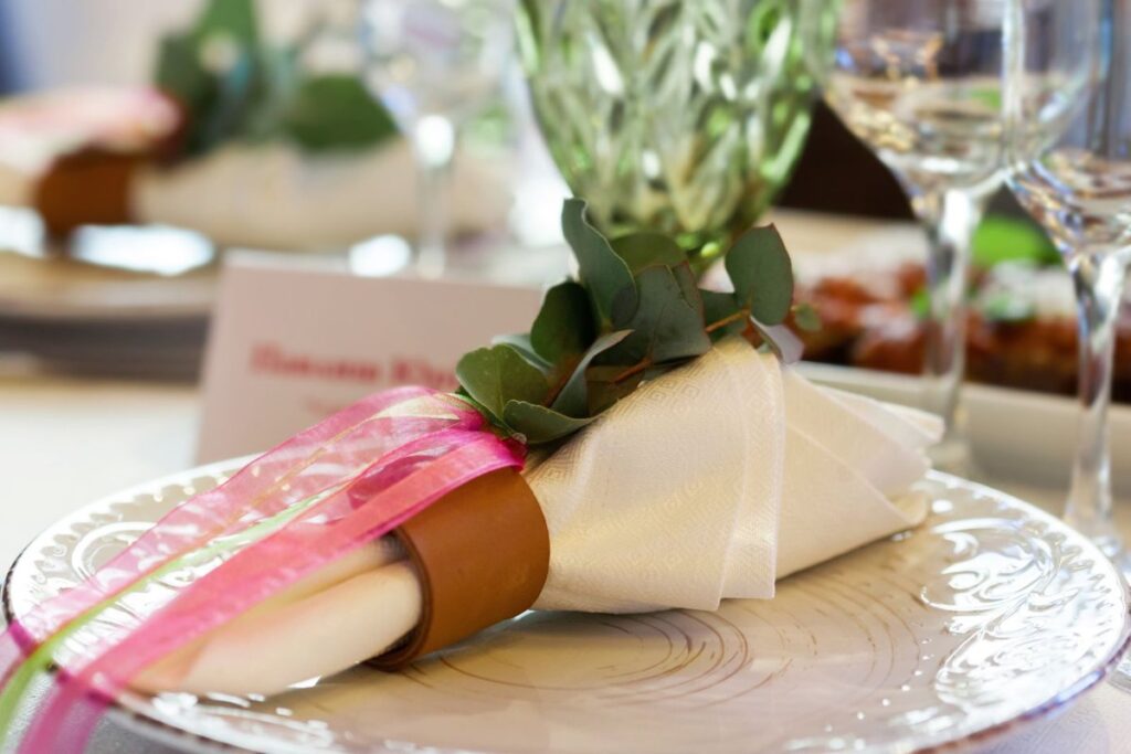 Folded napkin tied with ribbon and a eucalyptus sprig on a plate