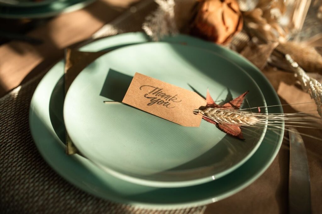Thank you place card on a green plate with dried wheat