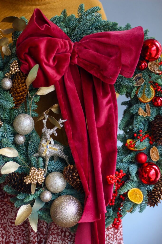 Christmas wreath with an oversized red velvet bow and ornaments