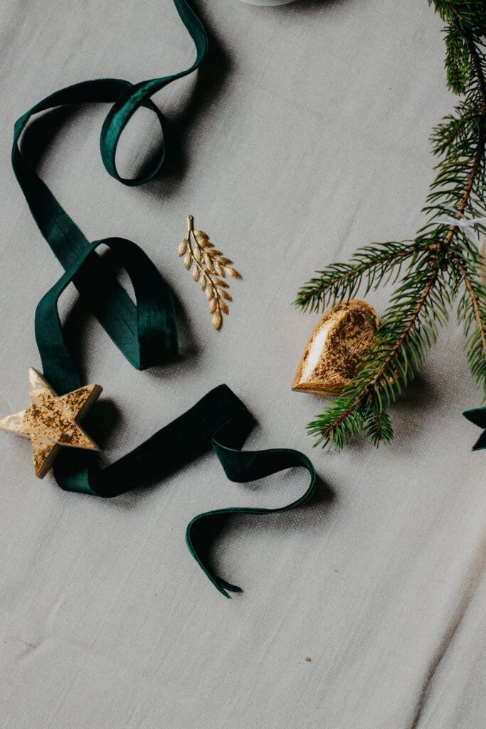 Dark green velvet ribbon with gold ornaments and pine on a flat lay