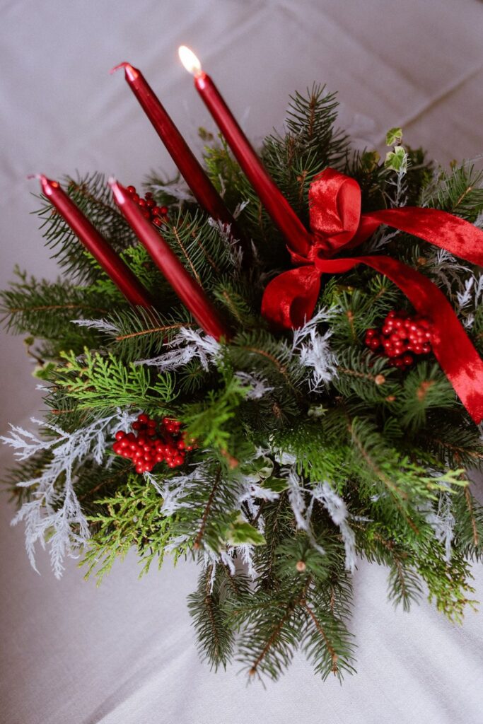 Red taper candles in an arrangement of greenery and red berries