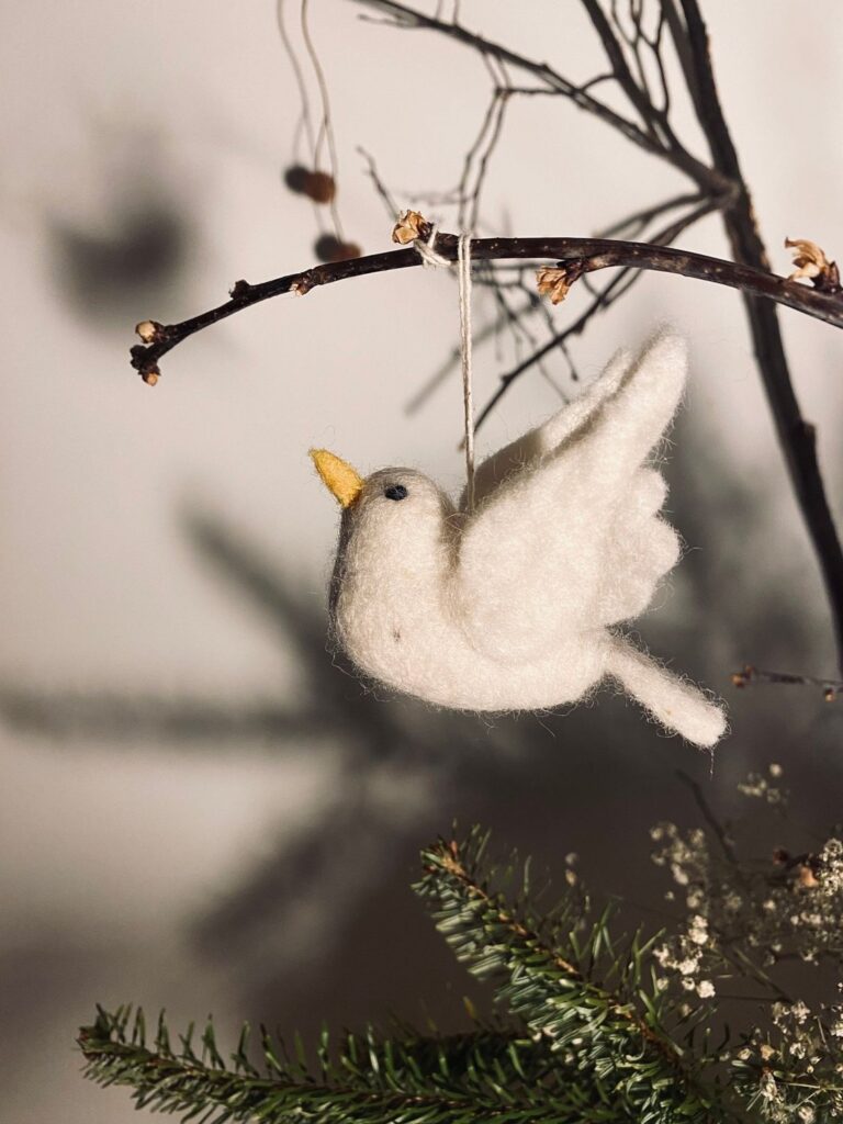 Handmade felt dove ornament hanging on a bare branch