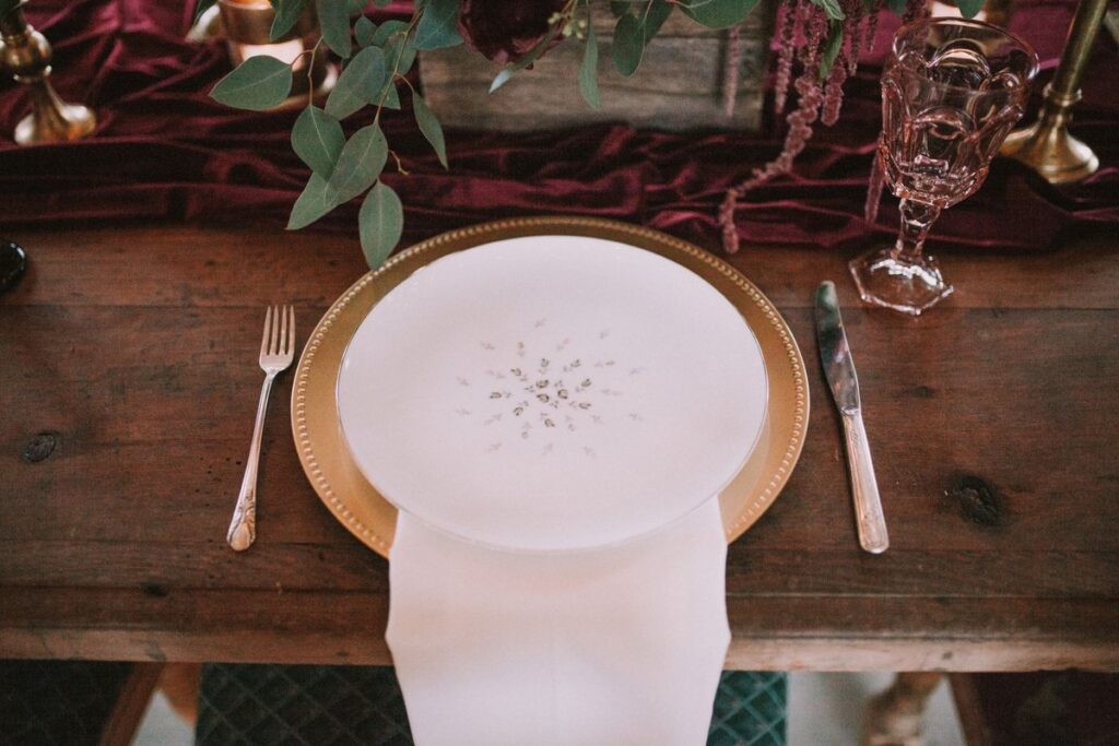 Gold charger plate with a white plate and napkin on a set table