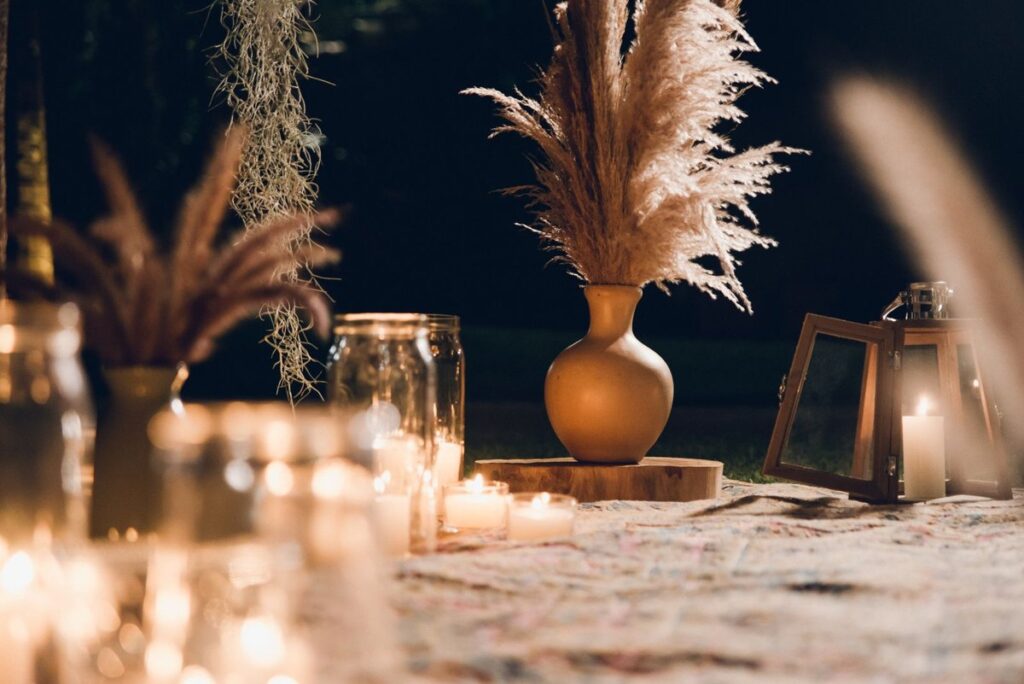 Pampas grass in a ceramic vase beside lit candles