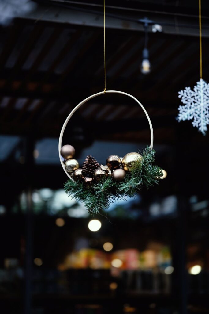 Metal hoop wreath with pinecones and baubles hanging in a room