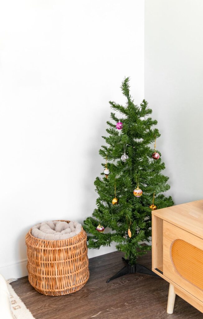 Small Christmas tree standing in a woven basket with ornaments