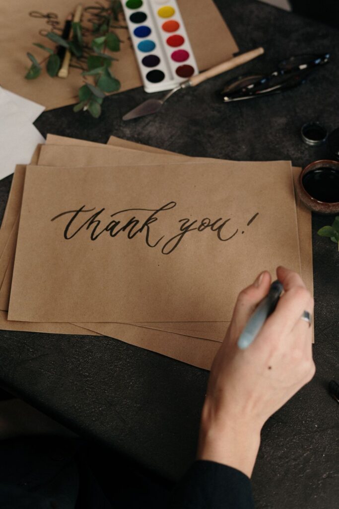 Hand lettering a thank you note on brown kraft paper