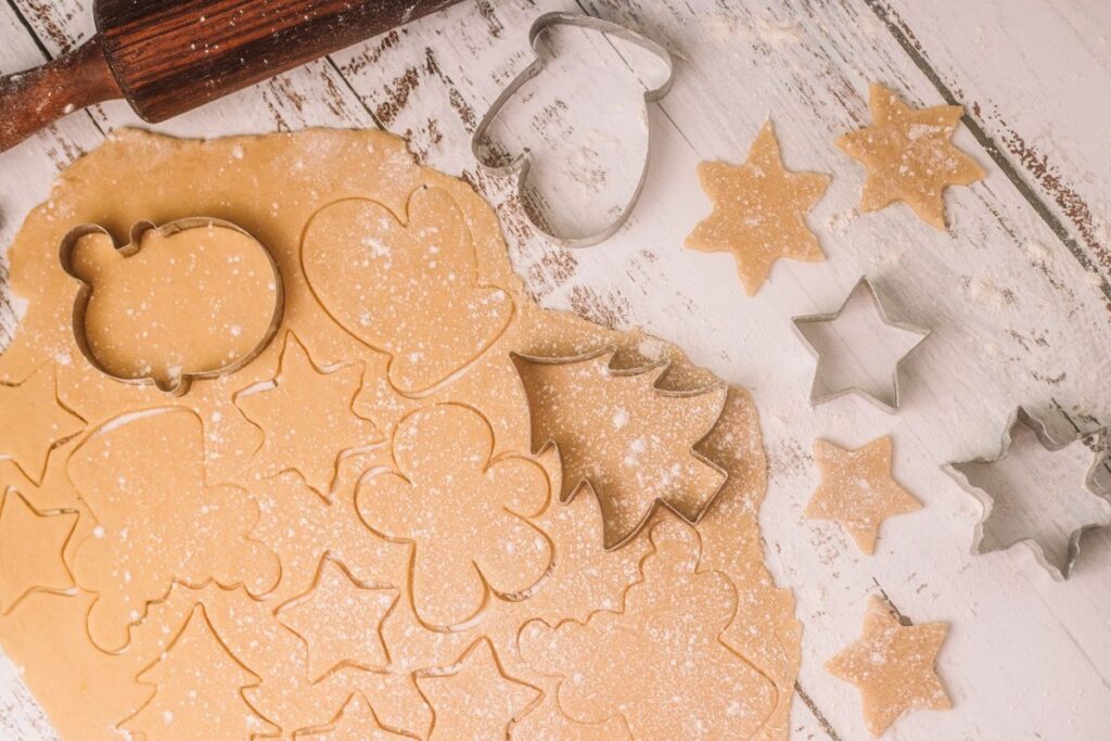 Cookie cutters pressing star and tree shapes into rolled dough