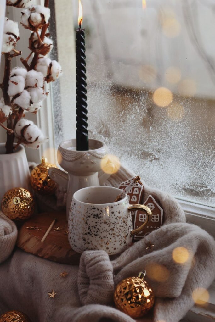 Windowsill with a candle, mug, cotton stems and ornaments
