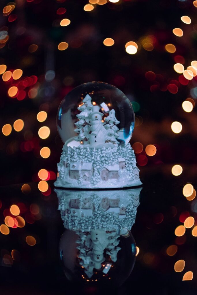 Snow globe glowing in front of warm Christmas bokeh lights