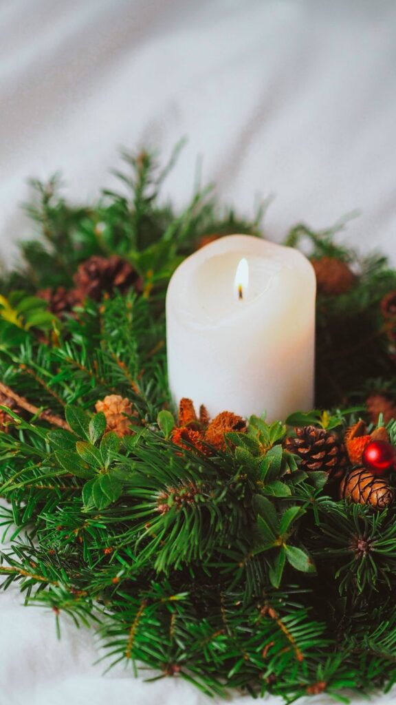 White pillar candle surrounded by conifer twigs and pinecones